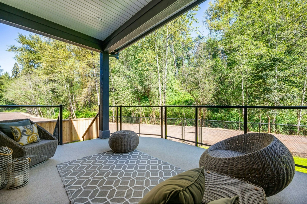 Covered outdoor patio with modern furniture overlooking forest